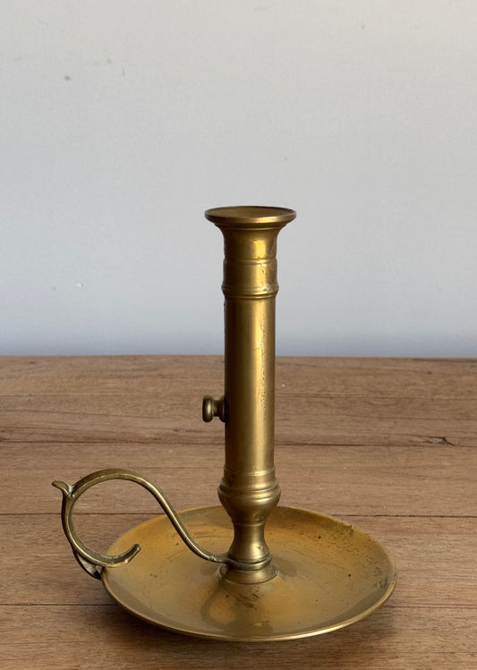 Brass candlestick holder on a wooden surface with a white background