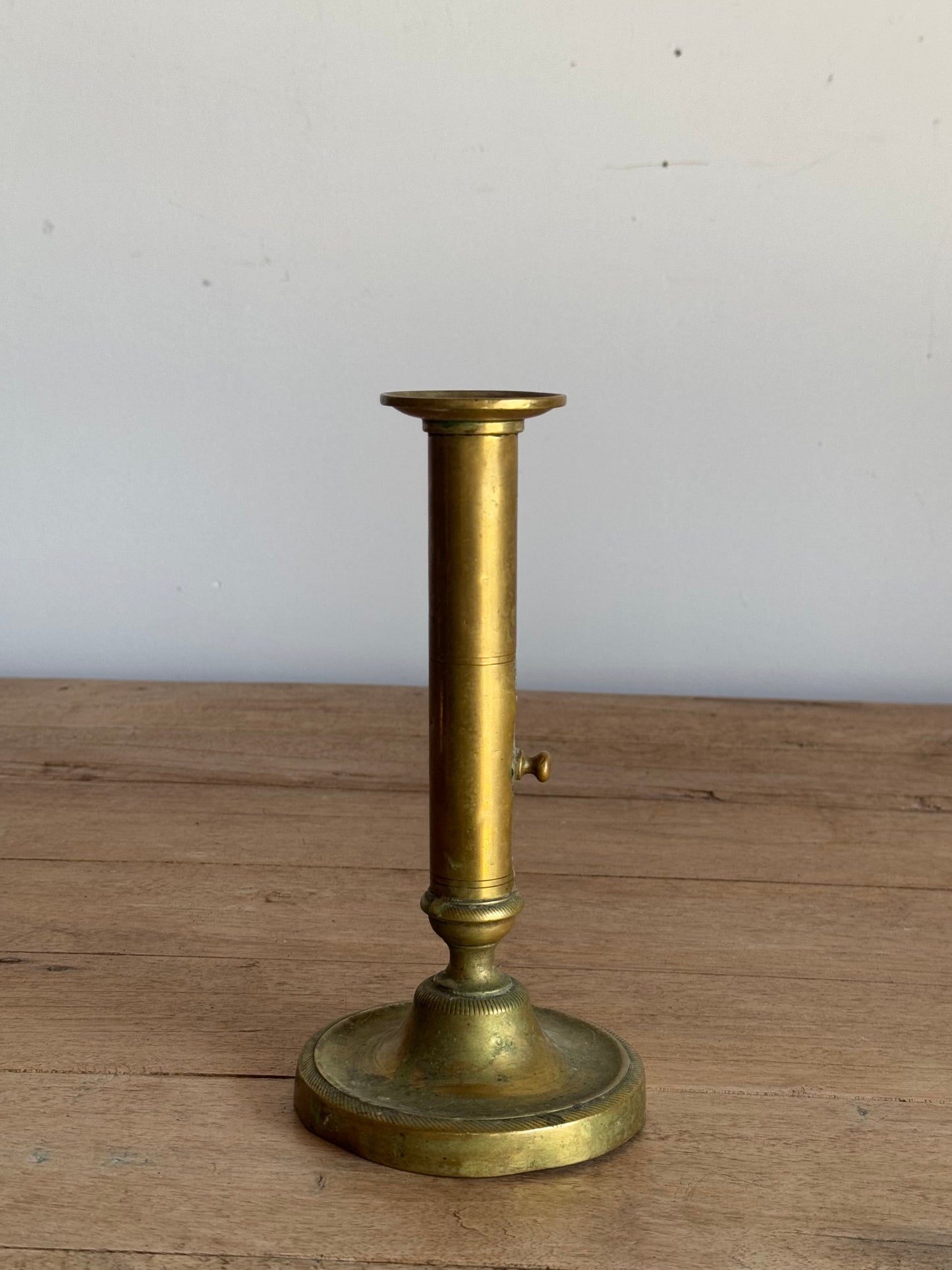 Brass candlestick holder on a wooden surface with a white background