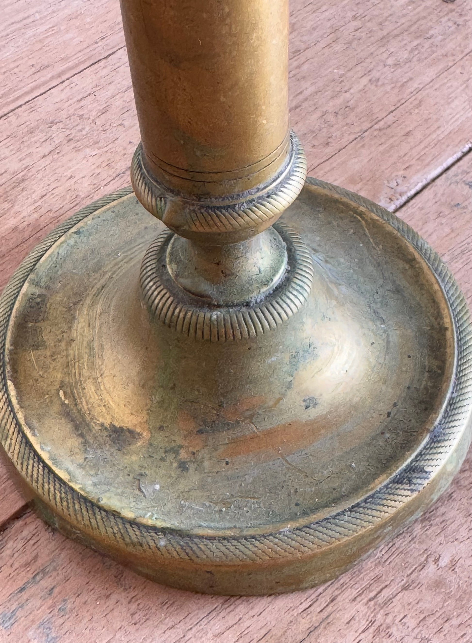 Brass candlestick base on a wooden surface