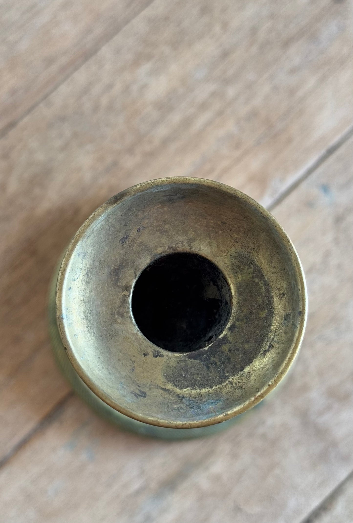 Bronze or brass cylindrical object with a central hole on a wooden surface