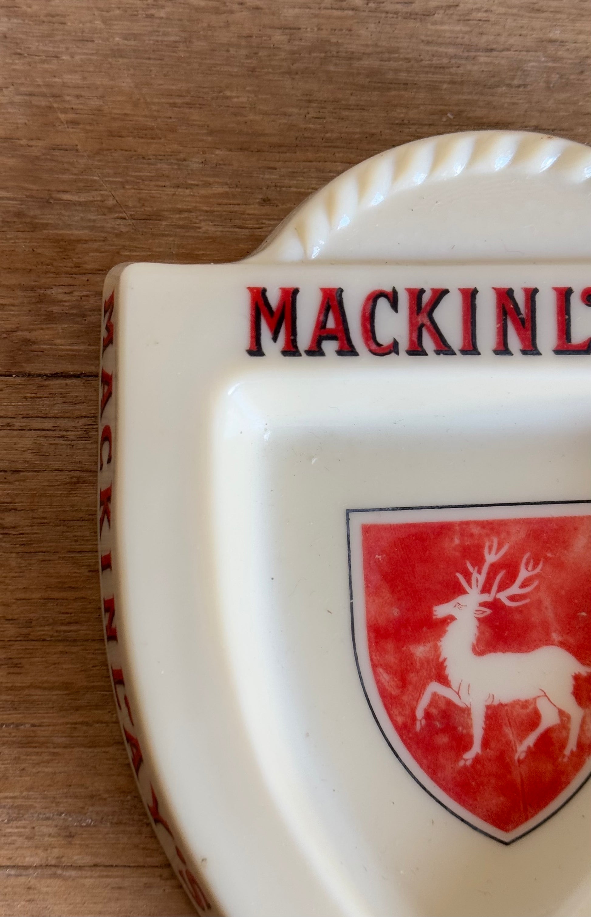 Decorative item with 'Mackinlay' text and deer emblem on a wooden surface