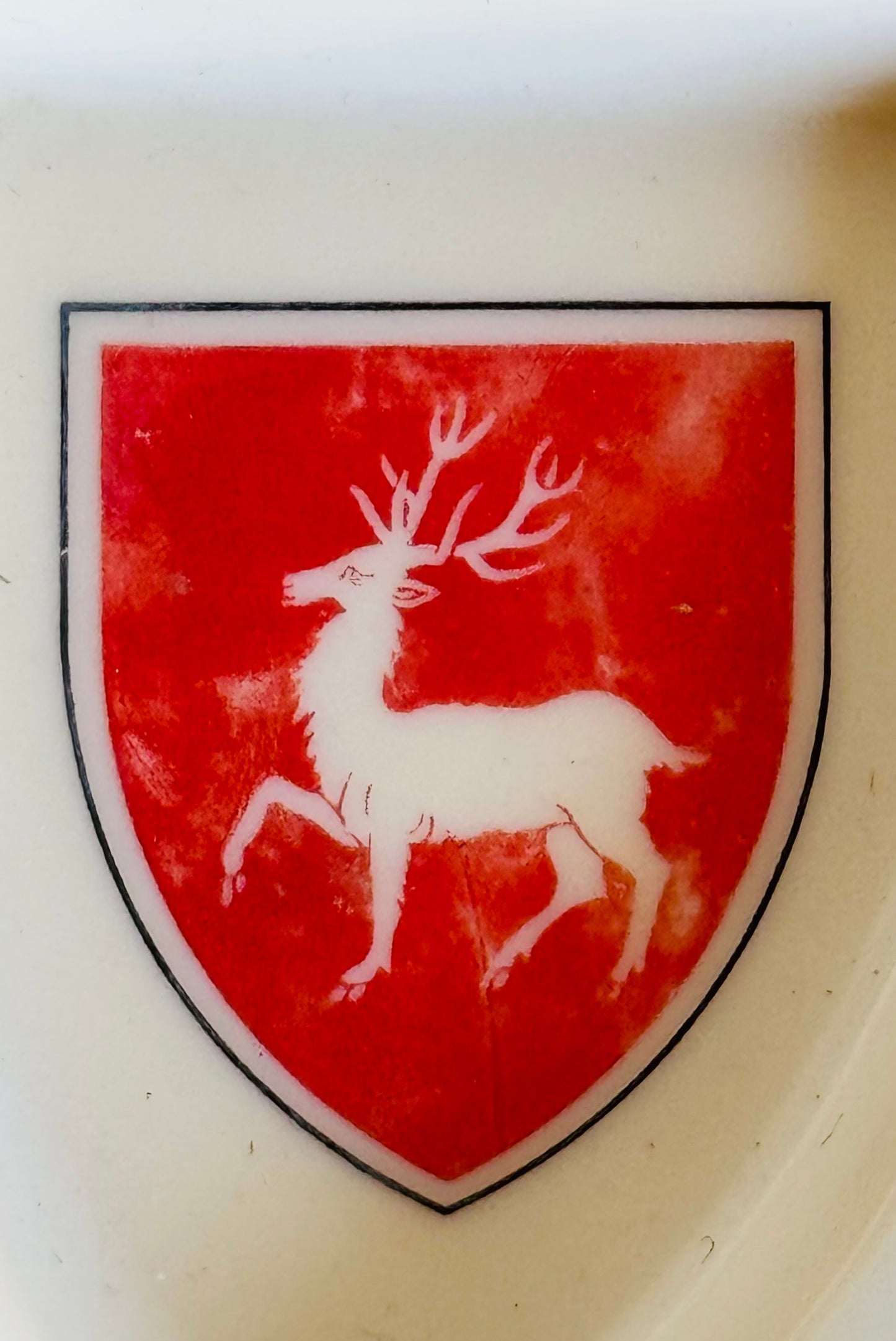Red shield with a white deer emblem on a beige background