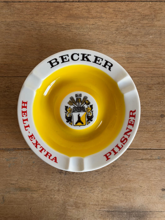 Vintage ashtray with 'Becker' and 'Pilsner' branding on a wooden surface