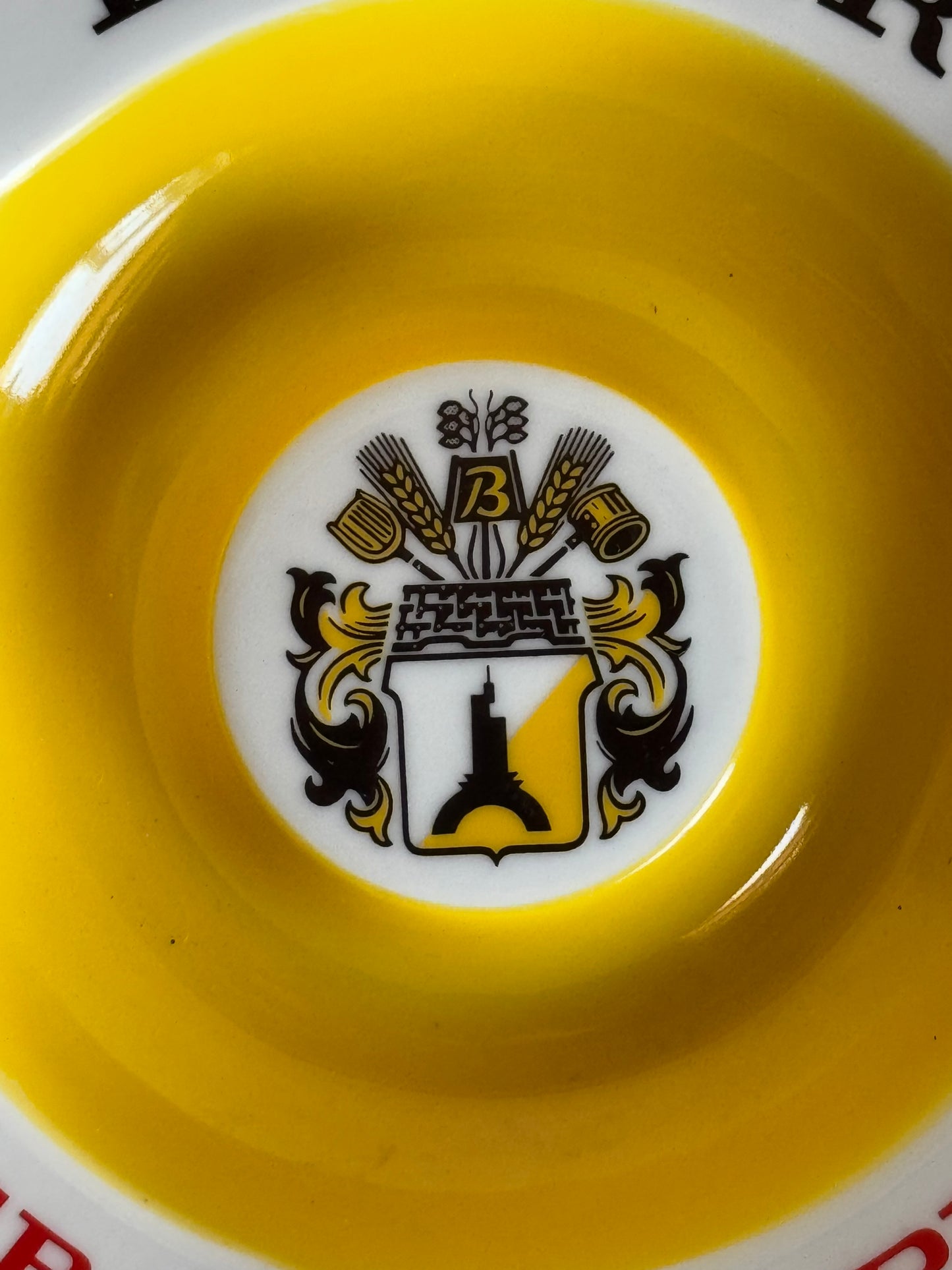 Yellow dish with a white center featuring a black and gold emblem