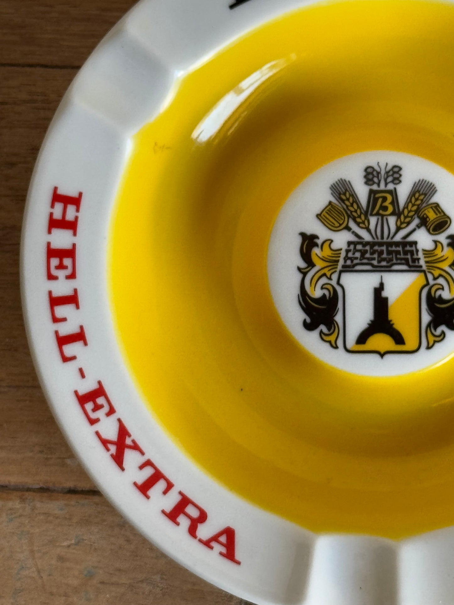 Yellow and white catch all dish with a logo and 'HELL-EXTRA' text on a wooden surface