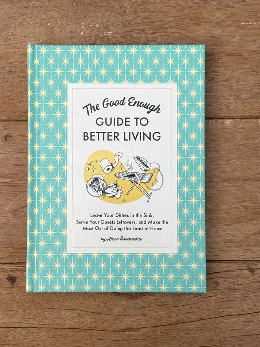Book titled 'The Good Enough Guide to Better Living' on a wooden surface