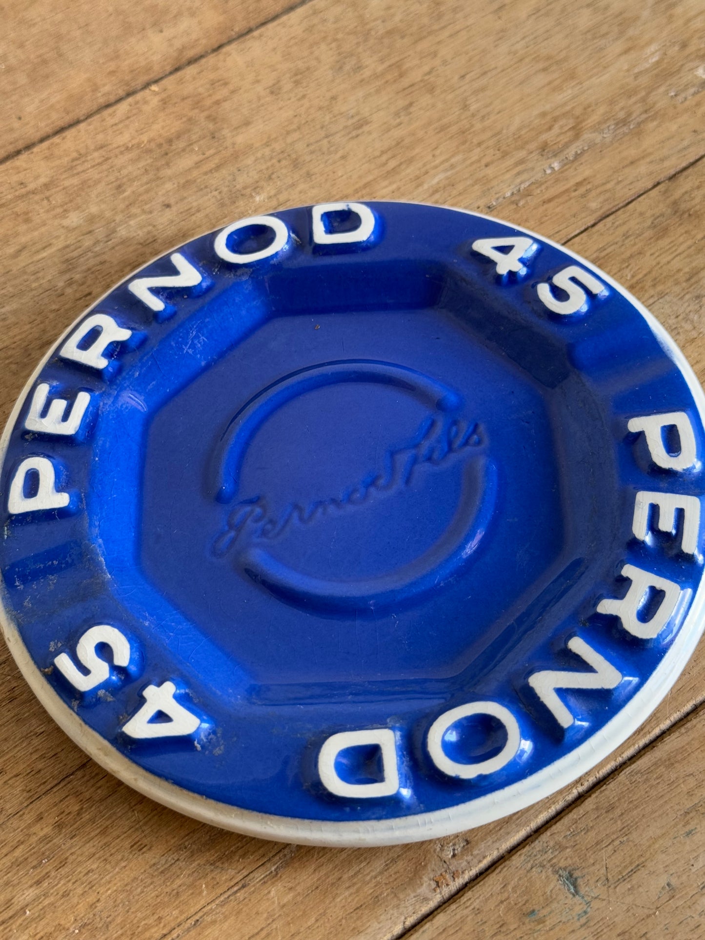 Blue and white Pernod catch all dish on a wooden surface