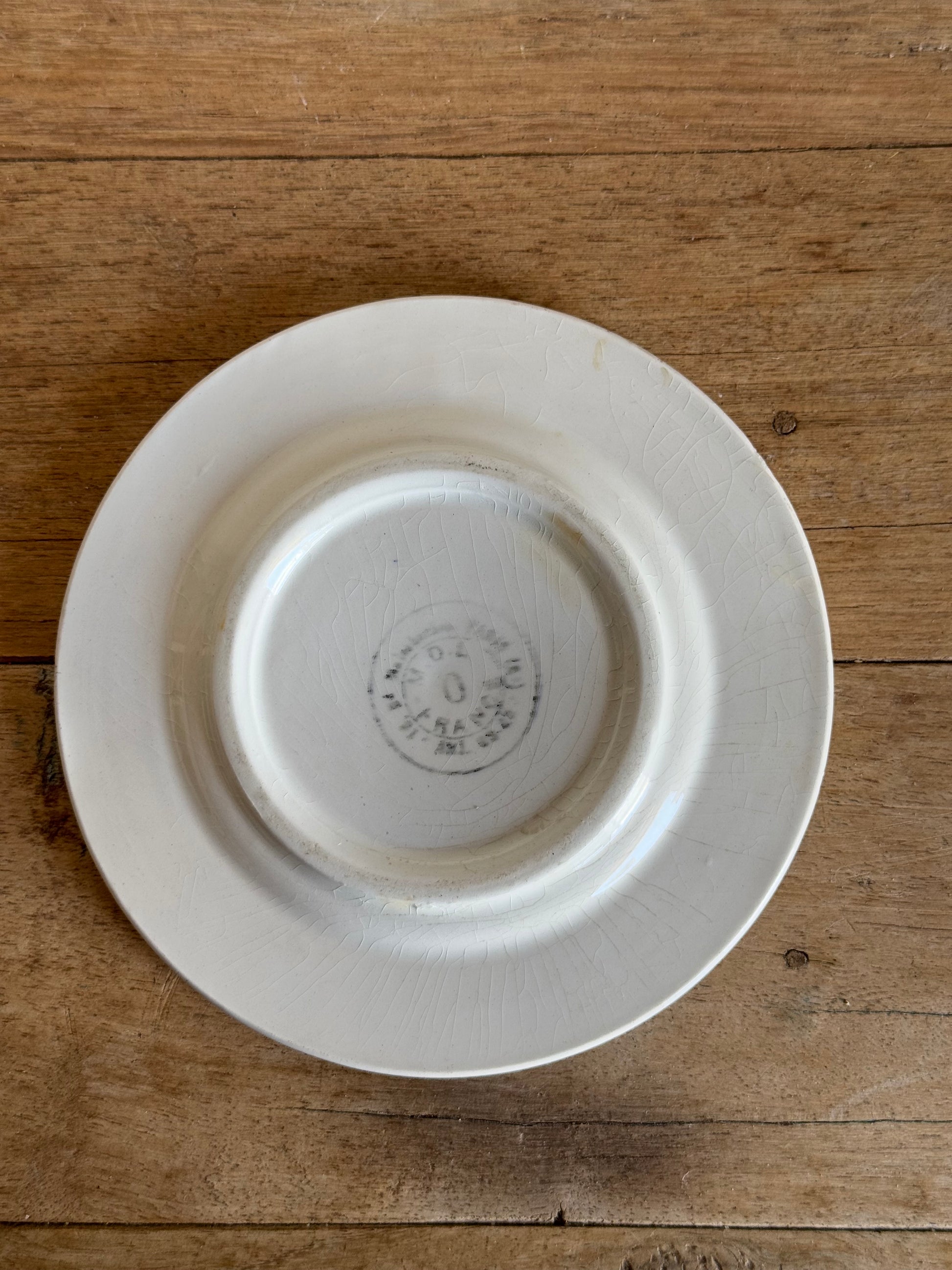White ceramic plate with a visible brand logo on a wooden surface