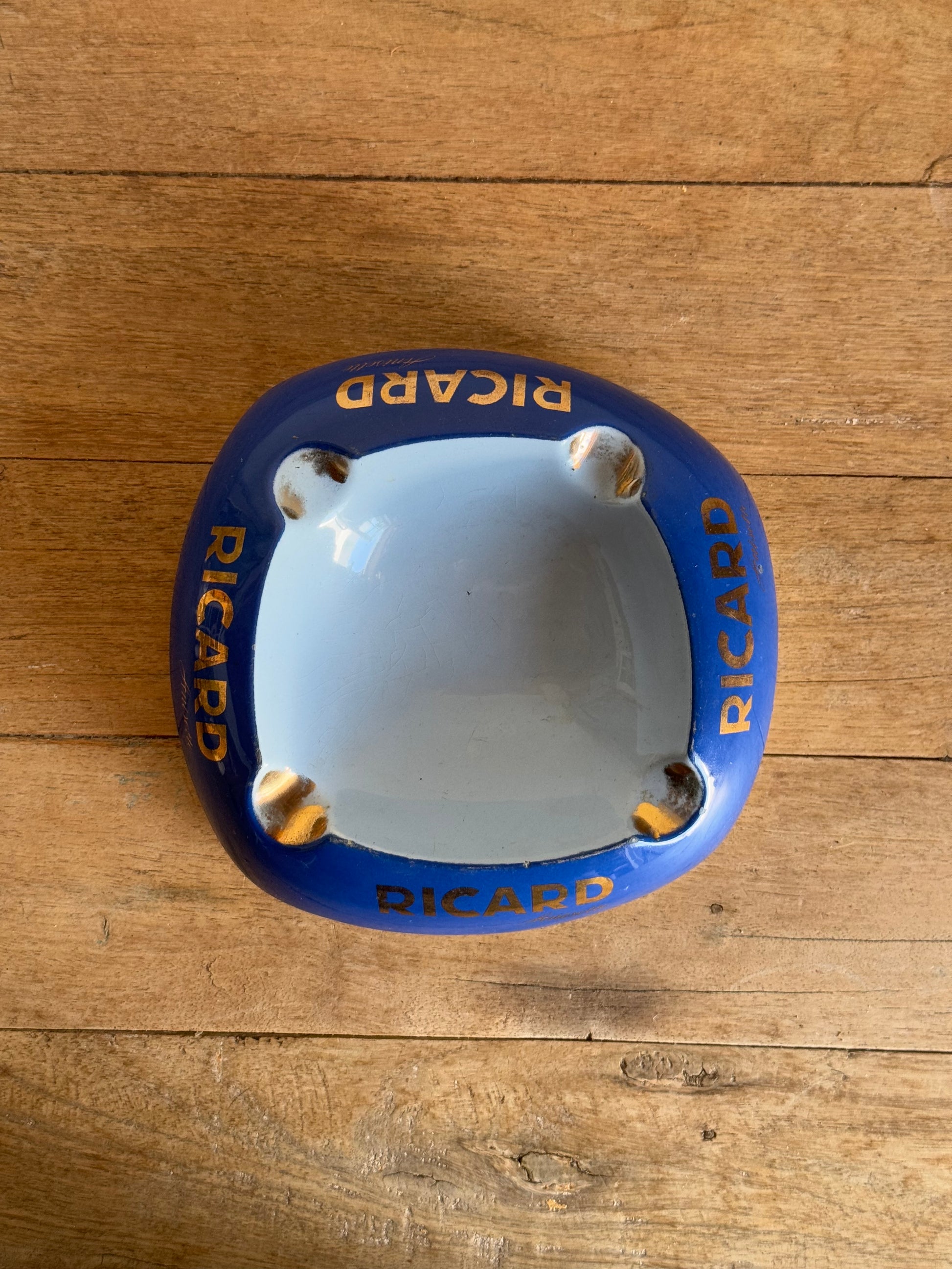 Blue and gold Ricard catch all dish on a wooden surface