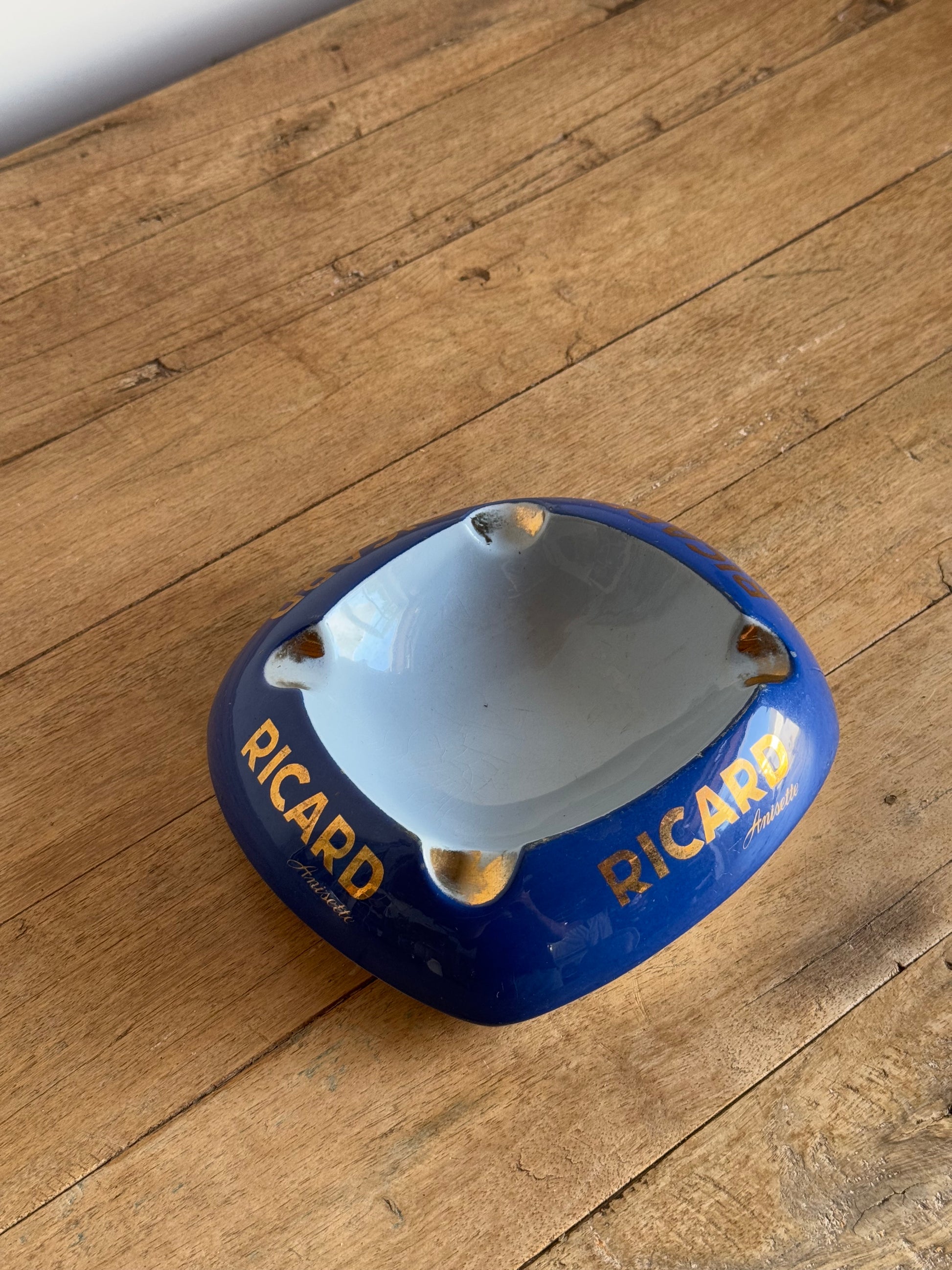 Blue catch all dish with 'Ricard' branding on a wooden surface