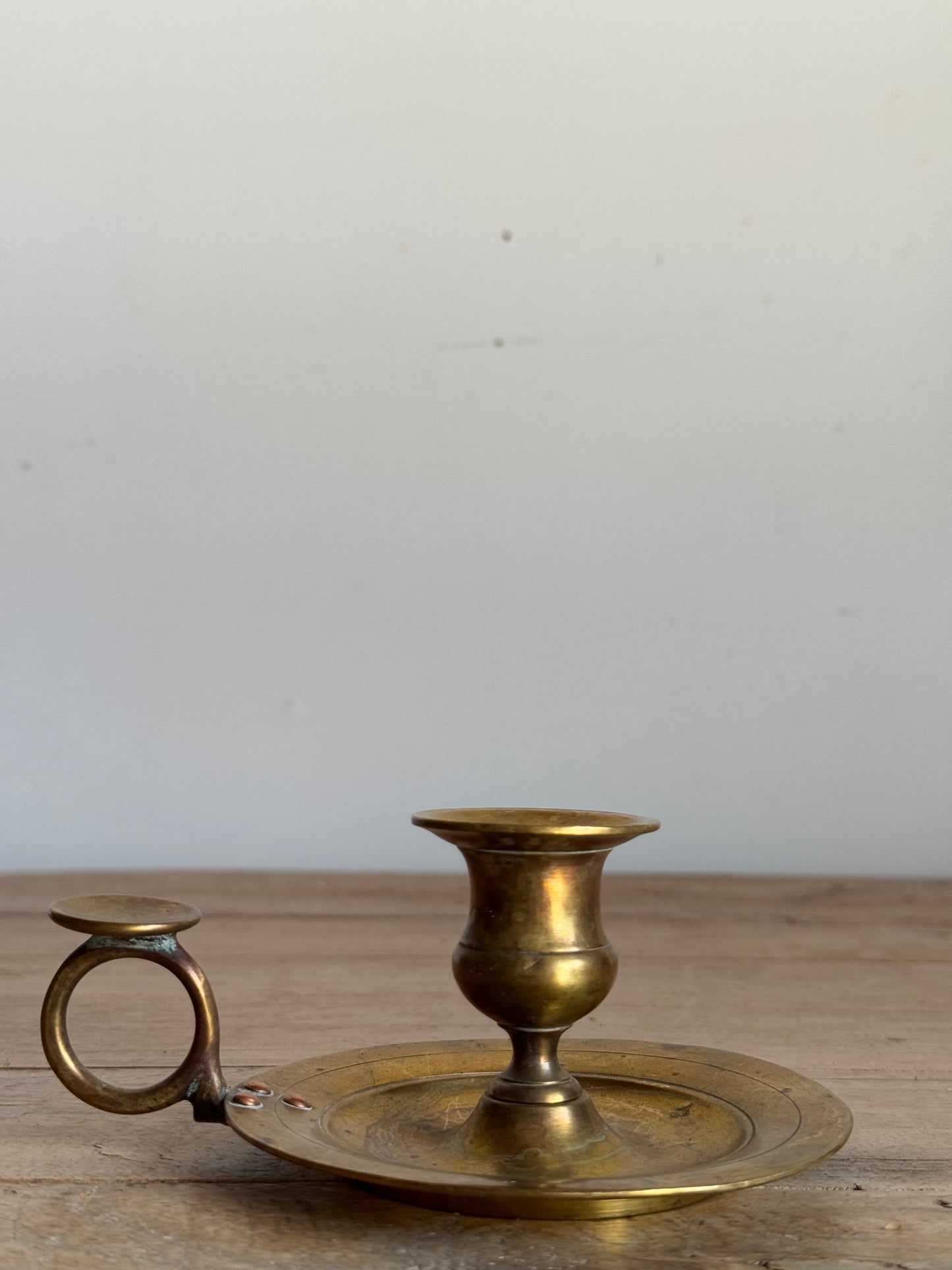 Brass candle holder with tray on a wooden surface