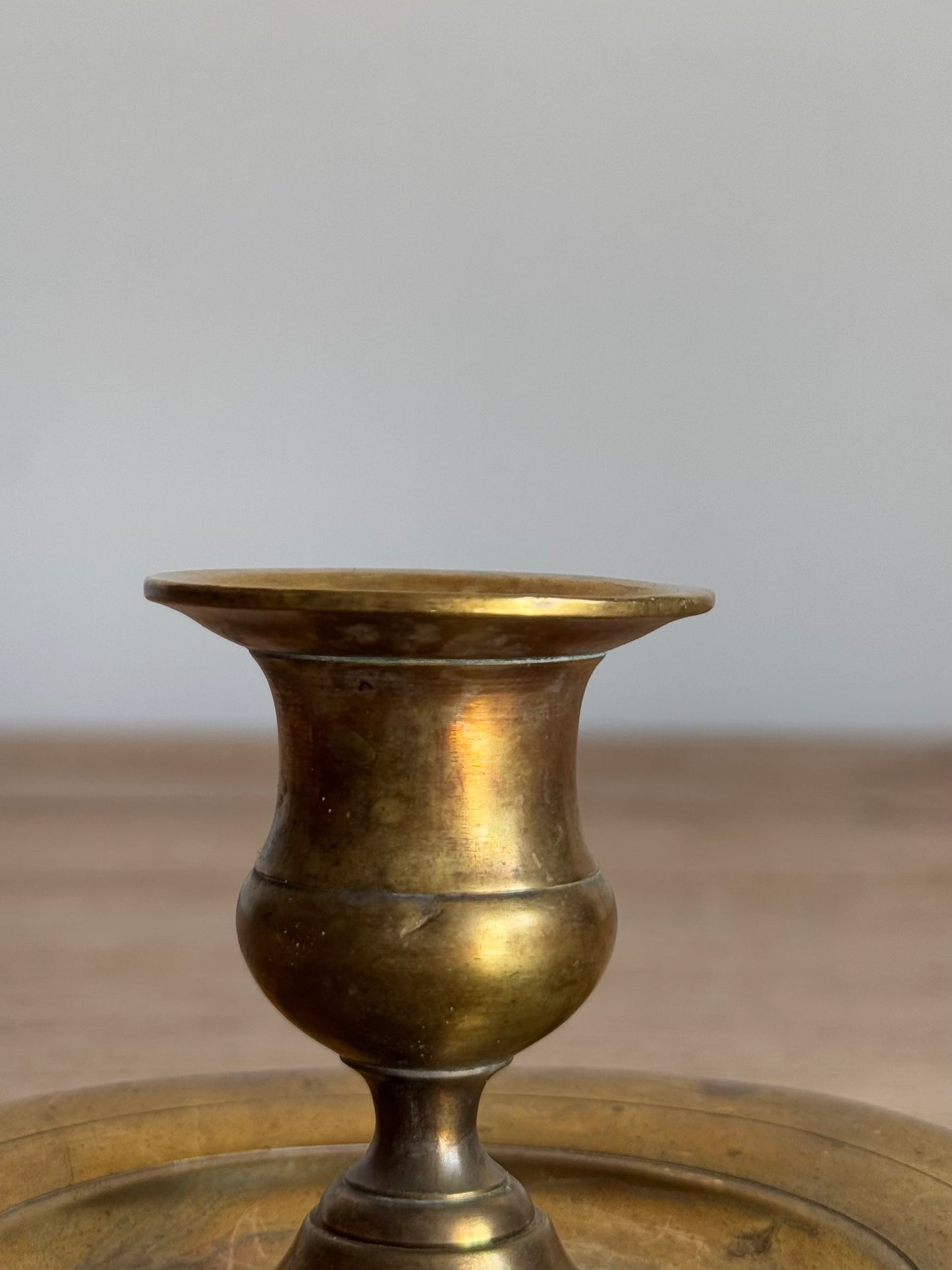 Bronze candlestick holder
 on a wooden surface with a neutral background