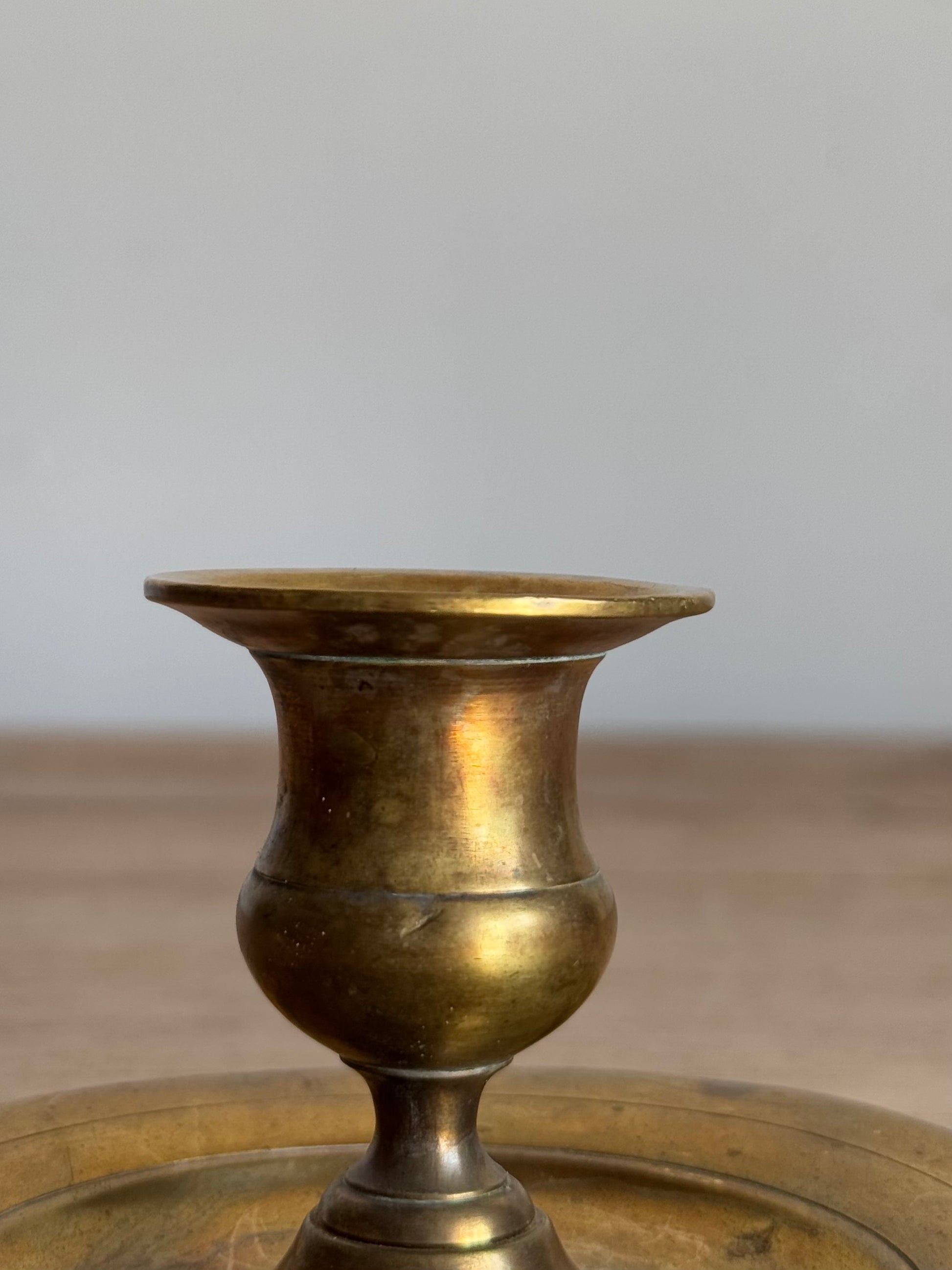 Bronze candlestick holder
 on a wooden surface with a neutral background