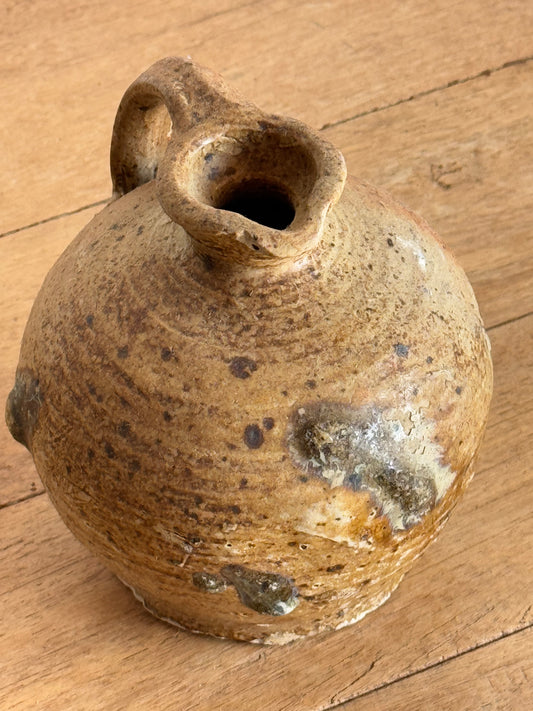Vintage ceramic pot with a worn surface on a wooden floor