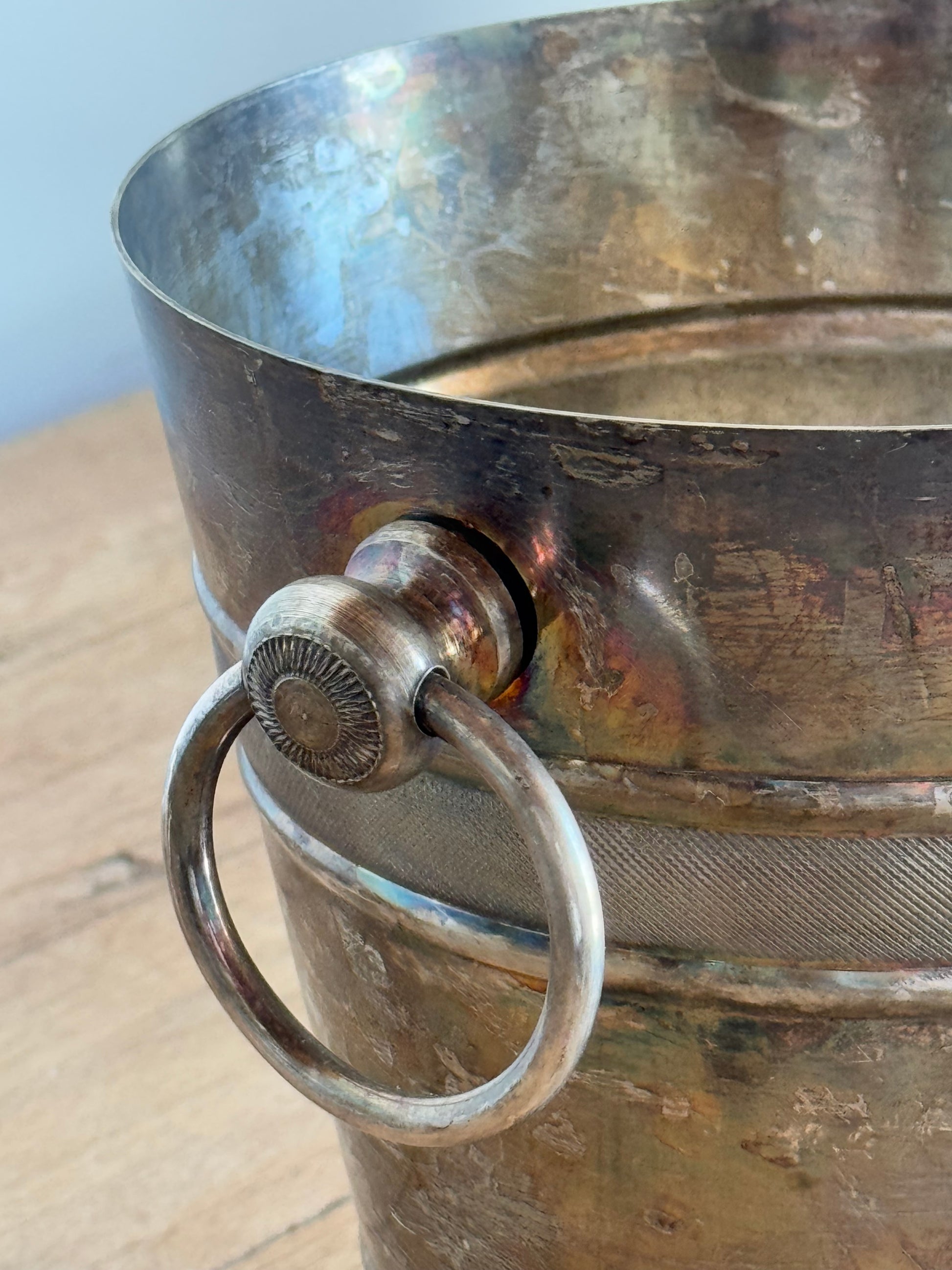 Close-up of a metallic ice bucket with a handle on a light background