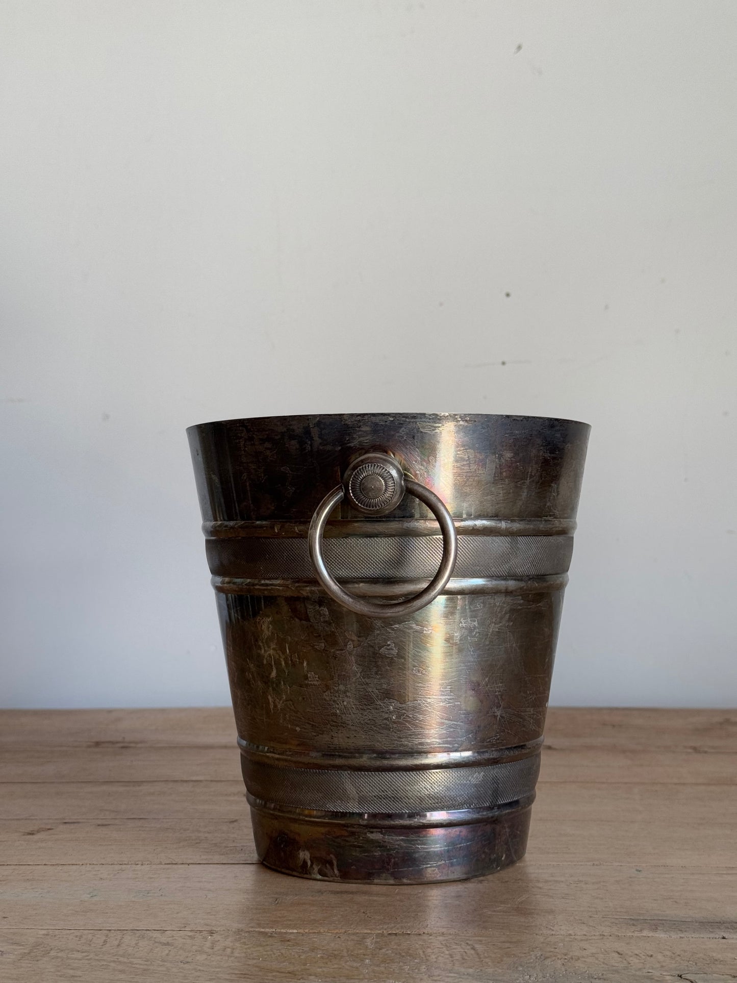 Vintage-style metal ice bucket on a white and wooden surface