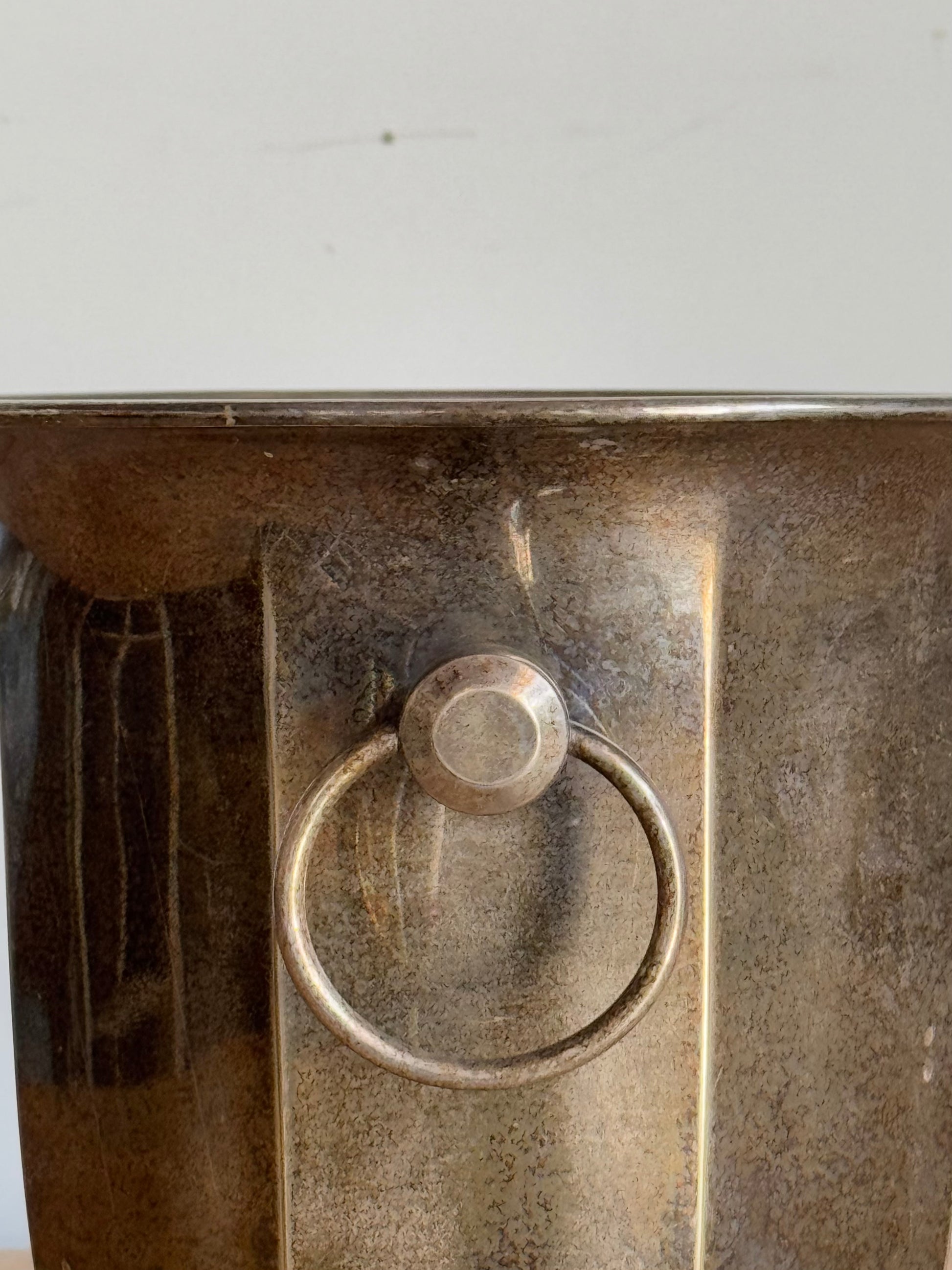 Metallic bucket with a circular ring handle on a plain background