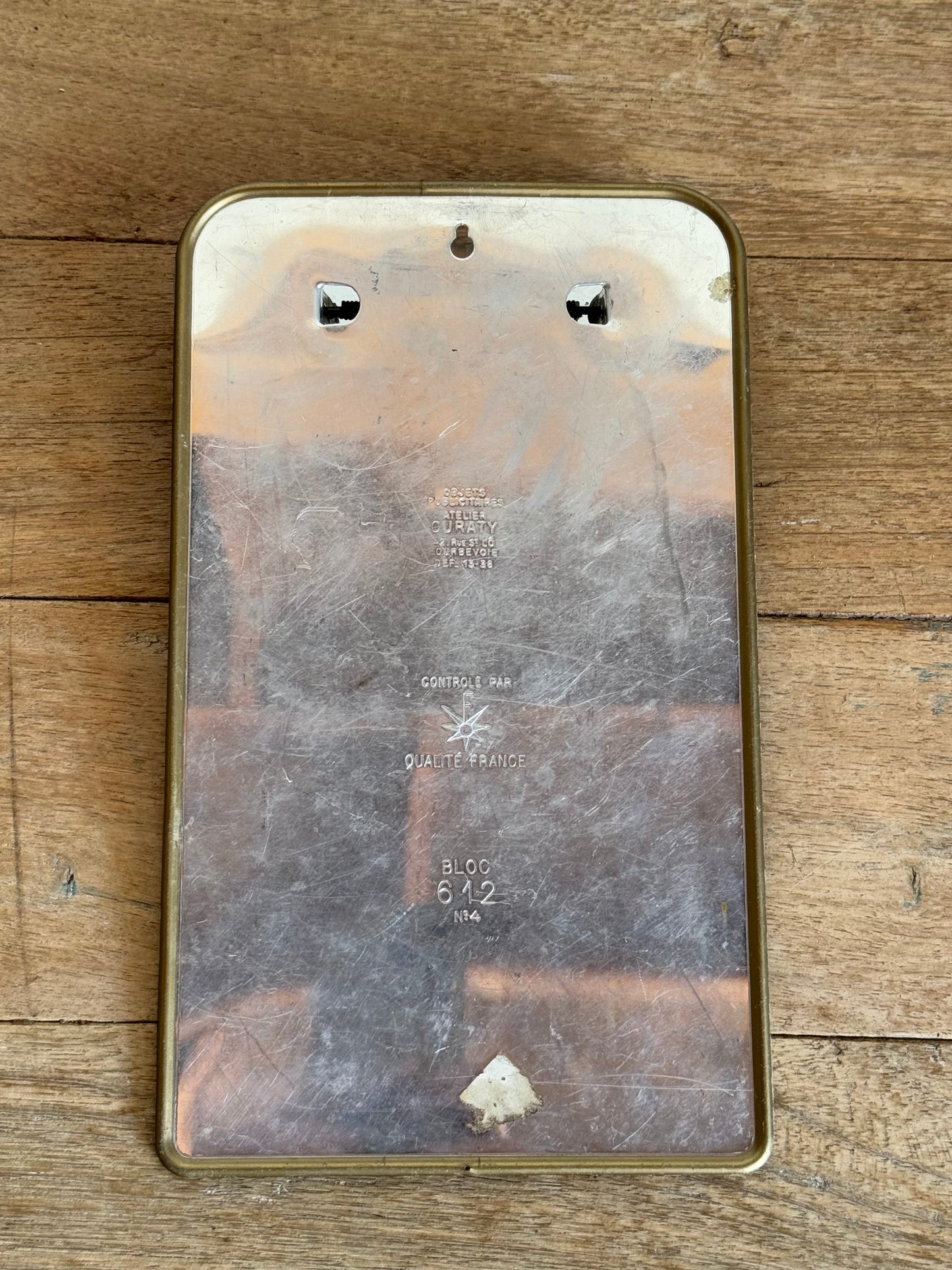 back of metal clipboard with engraved text on a wooden surface 