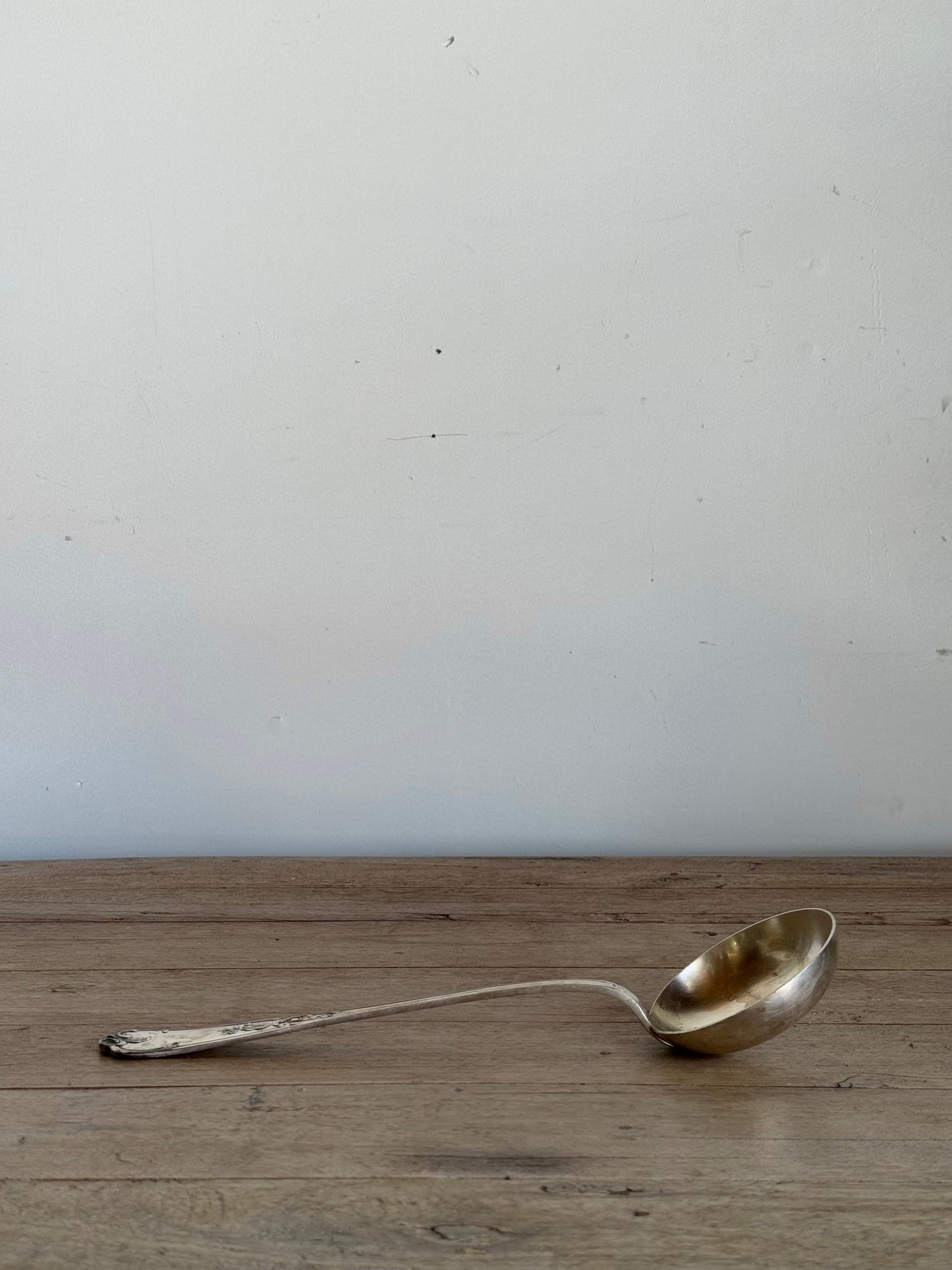 Metallic ladle on a wooden surface with a white background
