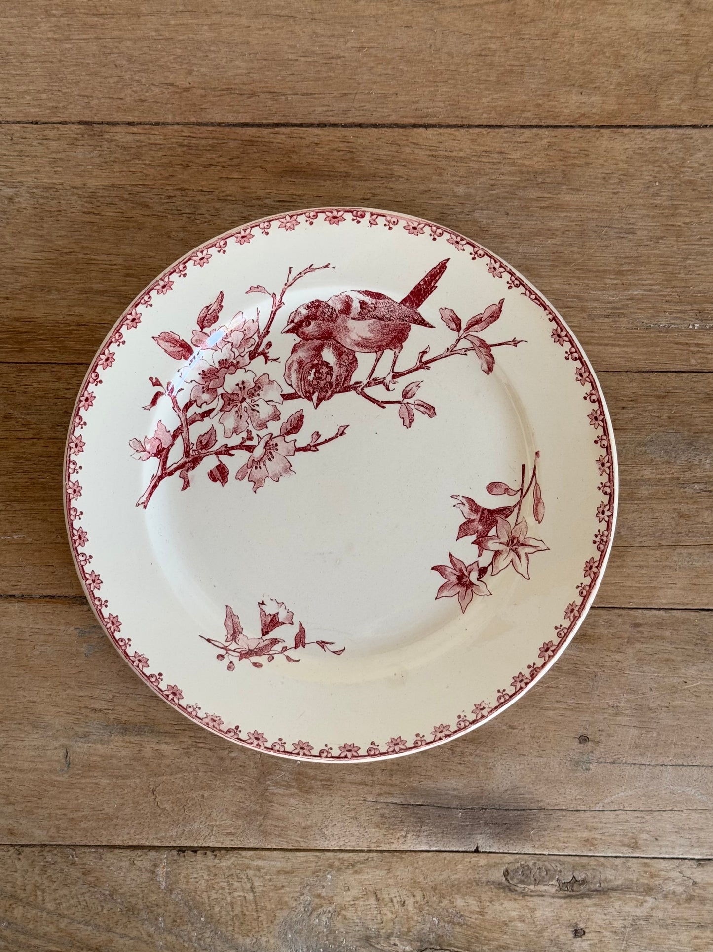 Decorative plate with floral and bird design on a wooden surface