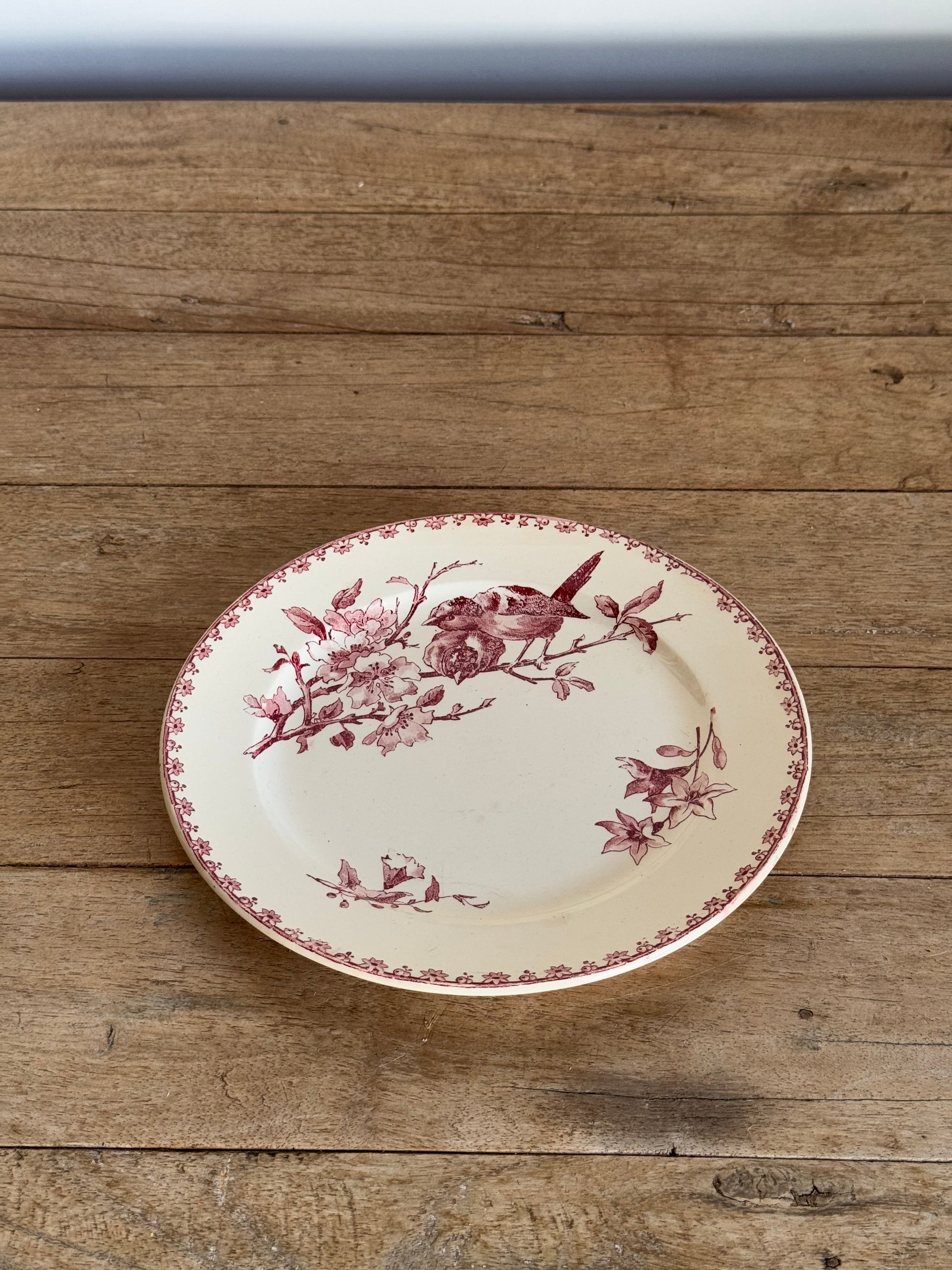 Decorative plate with floral and bird design on a wooden surface