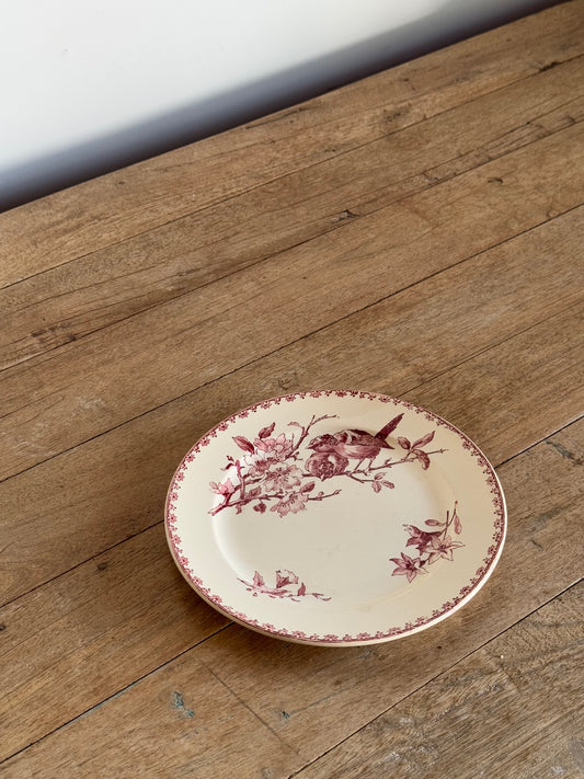 Decorative plate with floral and bird design on a wooden surface