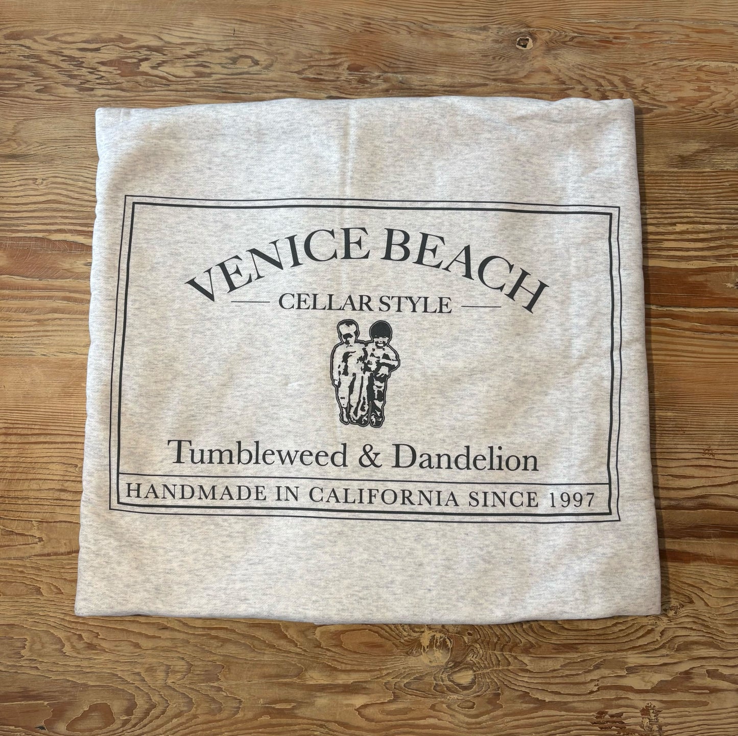 Beach blanket with 'Venice Beach' branding on a wooden surface