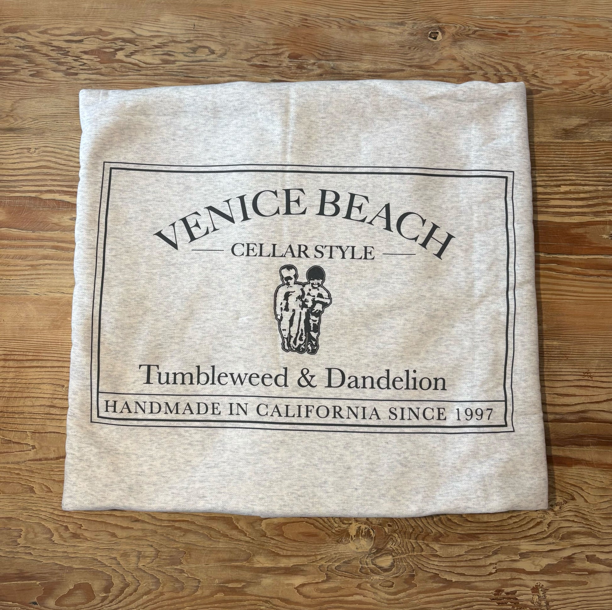 Beach blanket with 'Venice Beach' branding on a wooden surface