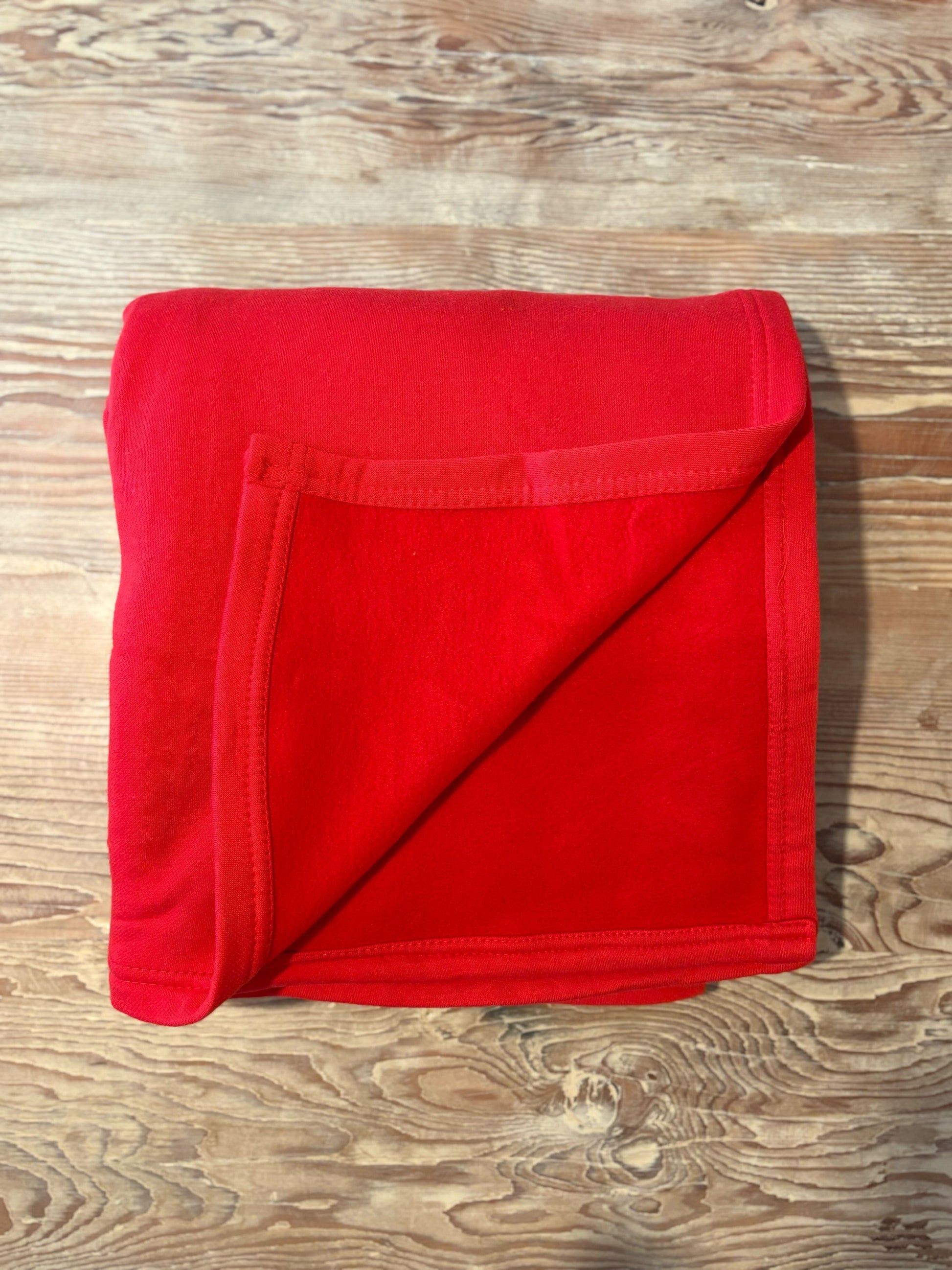 Folded red blanket on a wooden surface
