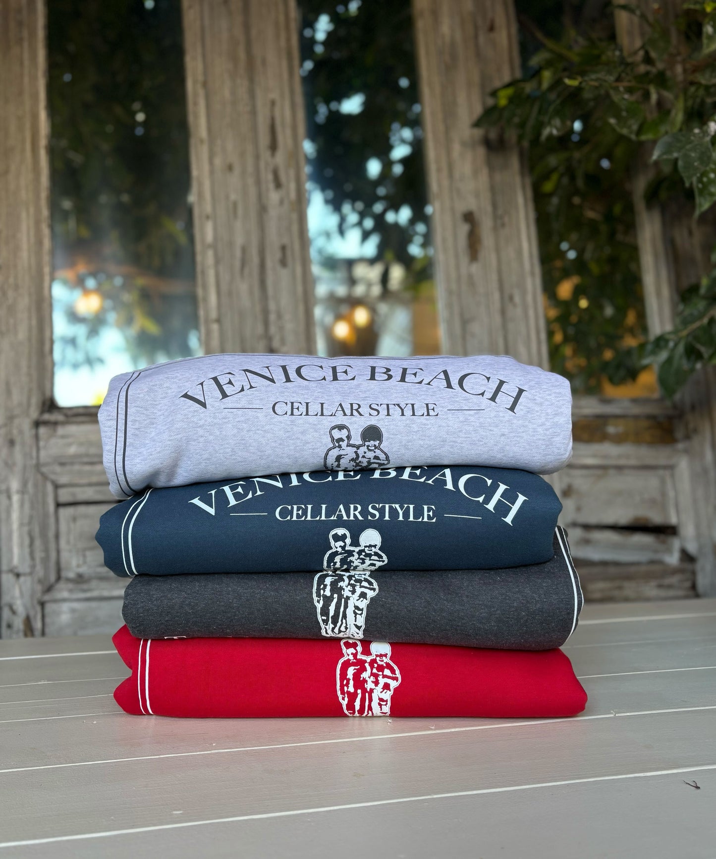 Stack of folded towels with 'Venice Beach Cellar Style' branding on a wooden surface.