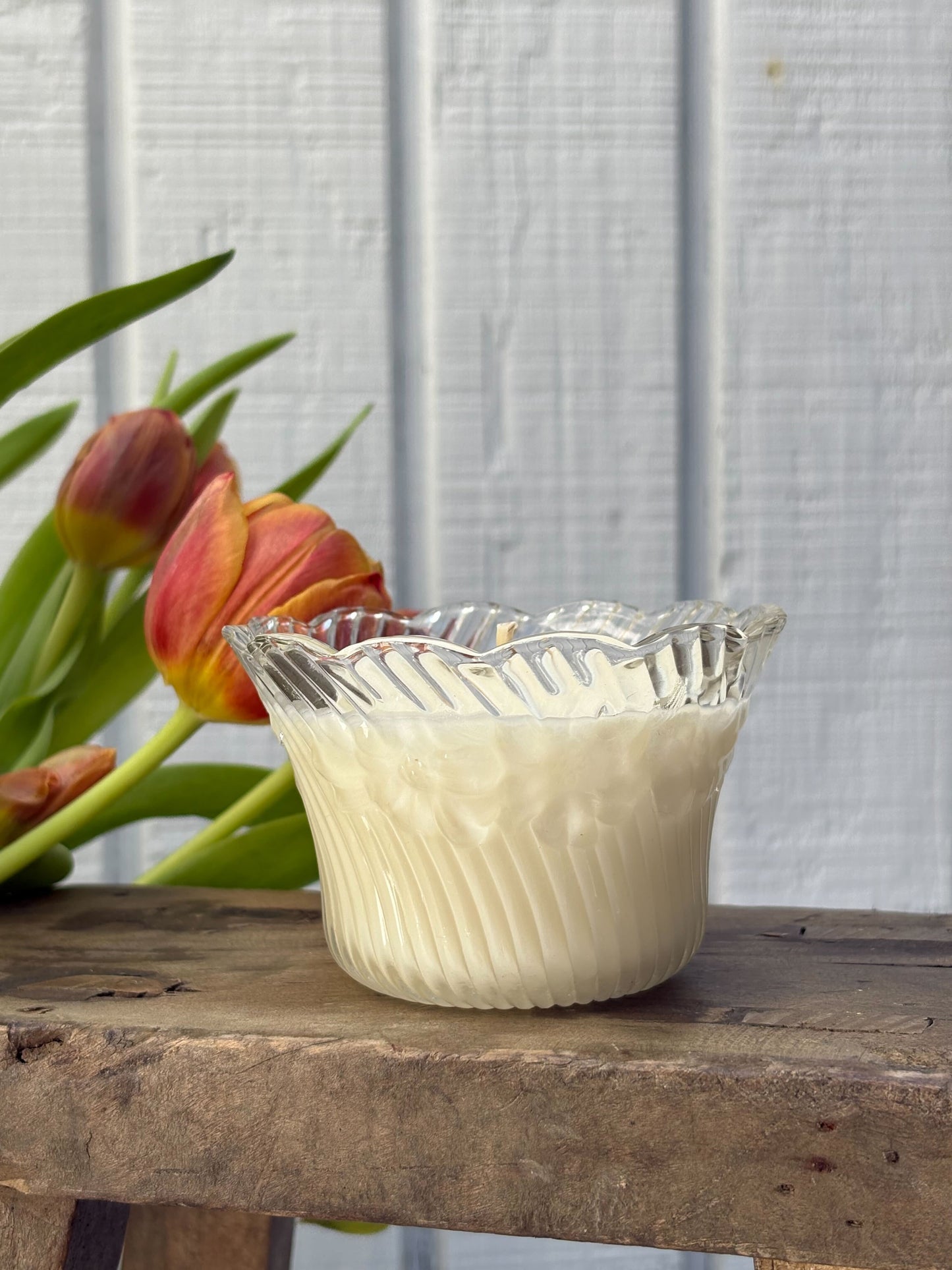 Clear glass bowl with white contents on a wooden surface with tulips in the background