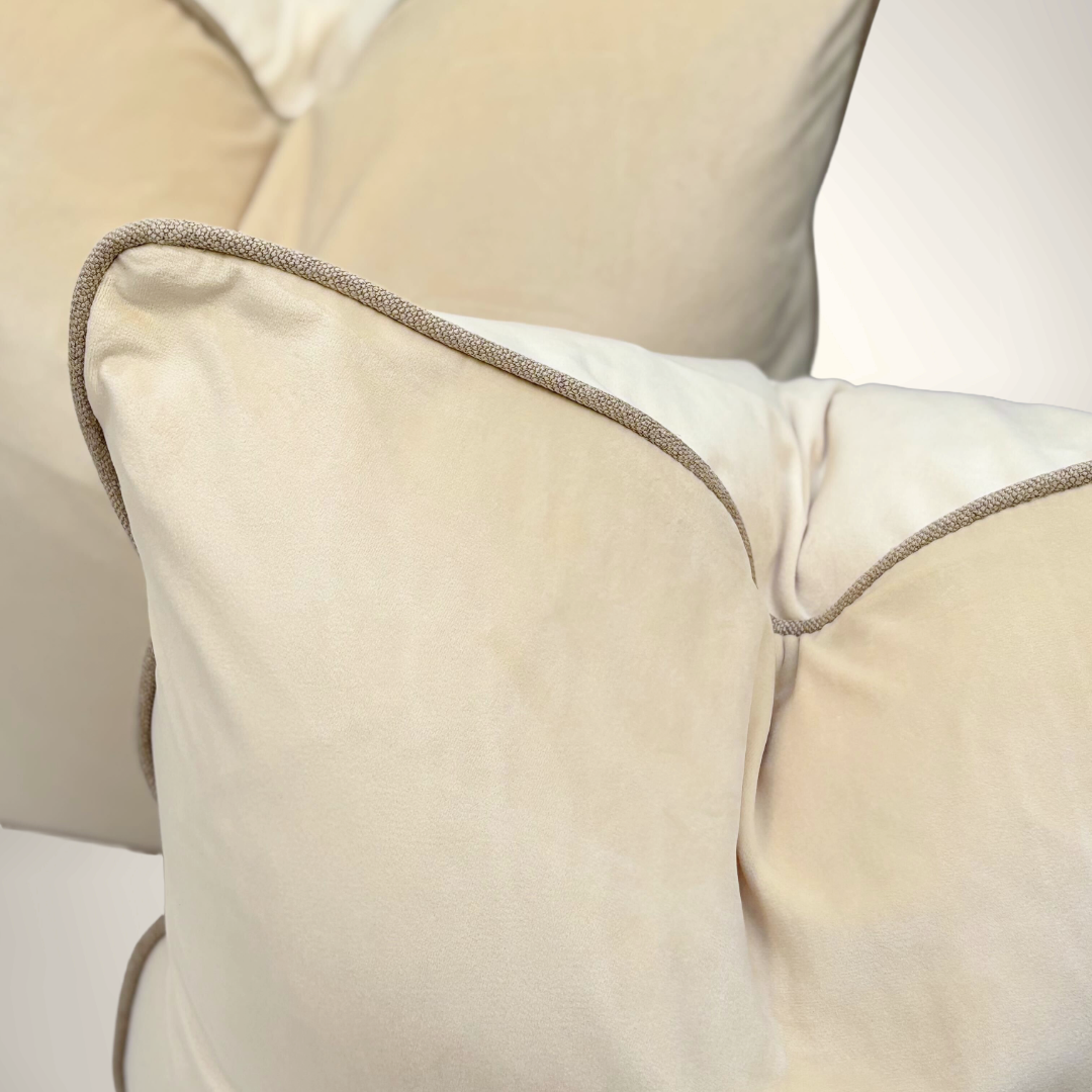 Close-up of beige pillows with a textured trim on a light background