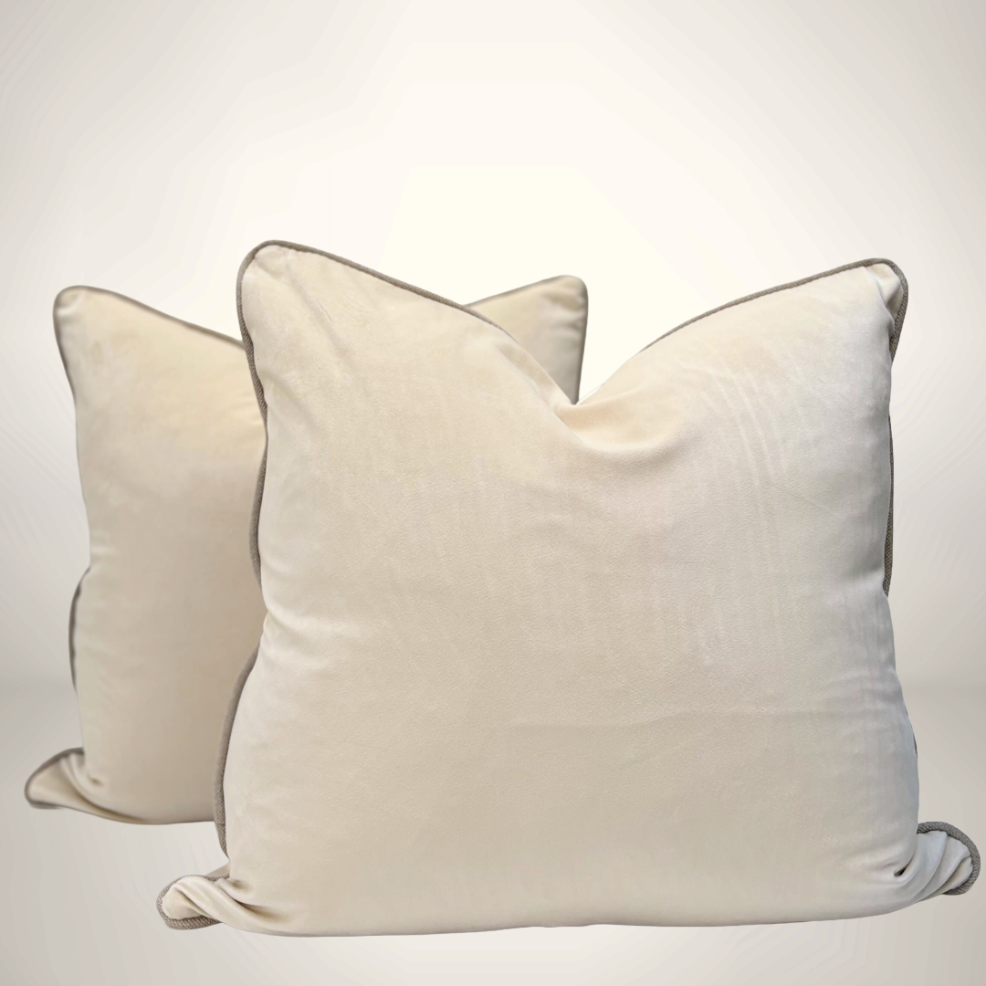 Two cream-colored pillows with dark brown edges on a light gray background