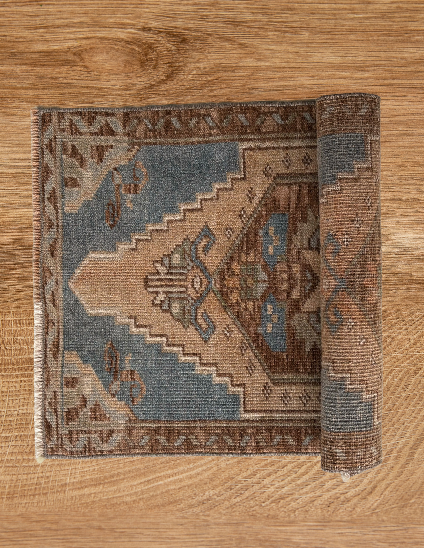Roll of patterned rug on a wooden floor