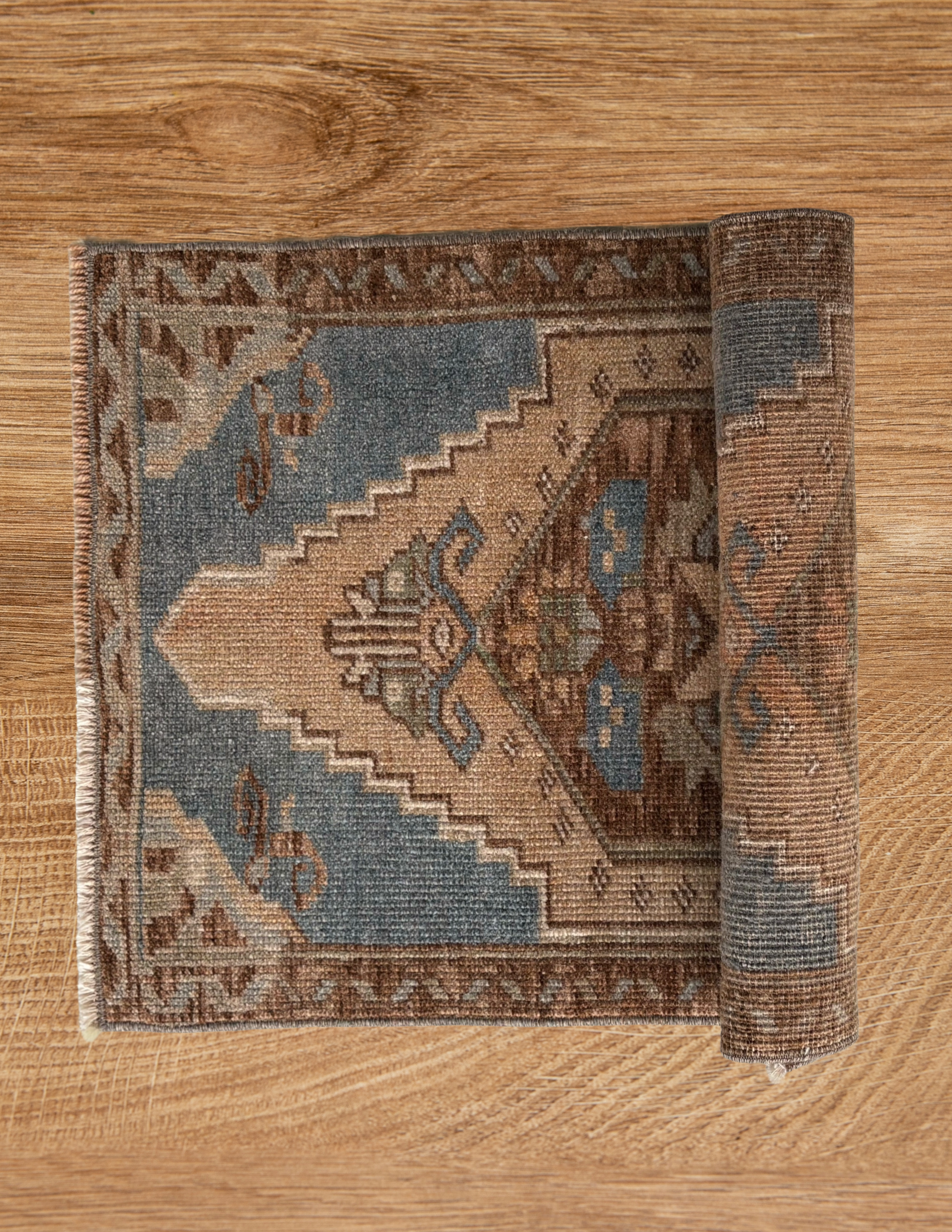 Roll of patterned rug on a wooden floor