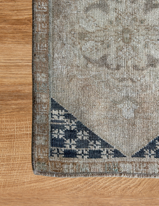 Corner of a patterned rug on a wooden floor