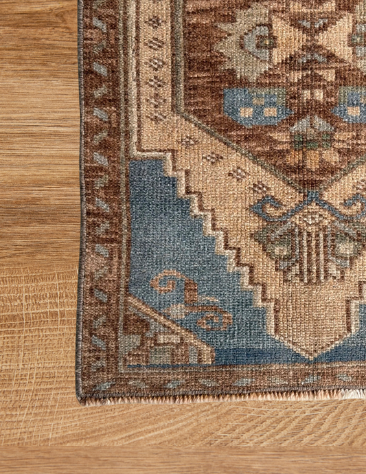 Corner of a patterned rug on a wooden floor