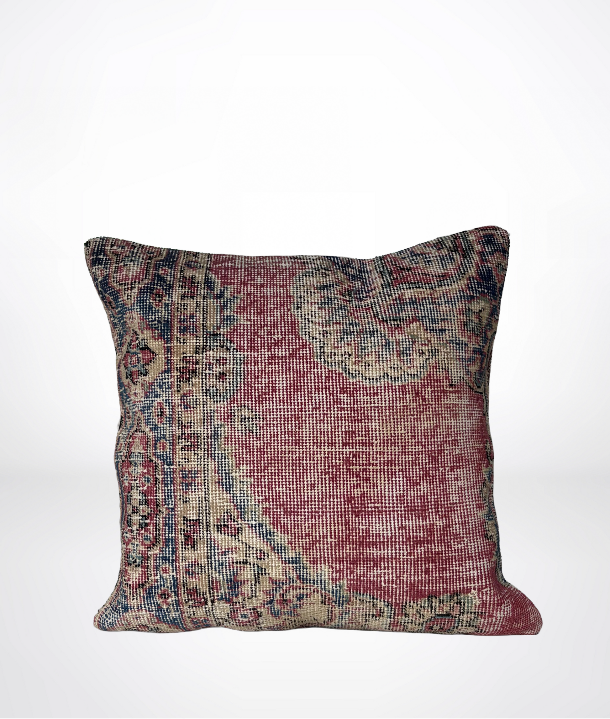 A square throw pillow featuring a distressed, vintage-style Persian or oriental rug pattern in muted red, beige, and blue tones, set against a plain white background.