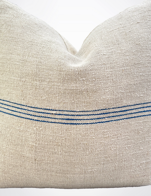 Textured beige pillow with blue stripes on a white background