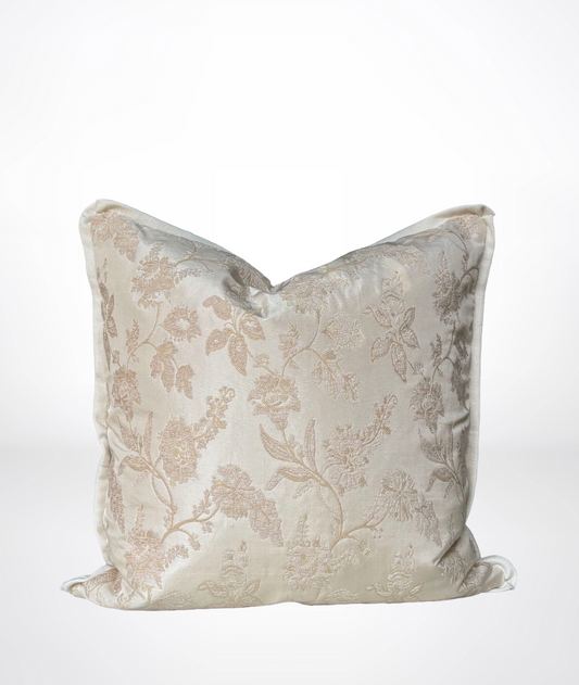 A square decorative throw pillow in a shimmering champagne beige fabric with a subtle tonal floral damask pattern, shown against a clean white background.