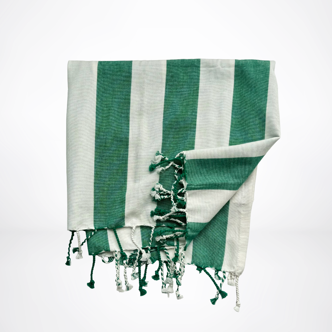 Green and white striped towel with tassels on a light gray background
