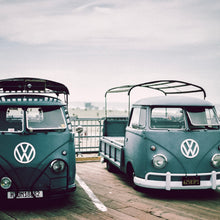 Load image into Gallery viewer, photo of two green vintage VW vans in parking lot at the beach