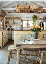 Load image into Gallery viewer, rustic cottage kitchen/dinig area, with baskets in ceiling rafters, vintage furniture, blue mason jar on table with green glass wine glasses on table