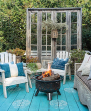 Load image into Gallery viewer, patio with turquoise painted wood deck with white medallions, white wood patio chairs with blue pillows, vintage wicker sofa, fire pit and large upright old windows as backdrop