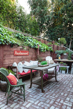 Load image into Gallery viewer, brick floor outdoor living space with vintage furniture, red and white pillows and red sign that says &quot;restaurant&quot; hanging on wooden hill support