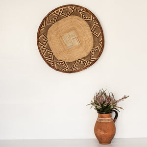 Round woven wicker tray with tan and brown pattern