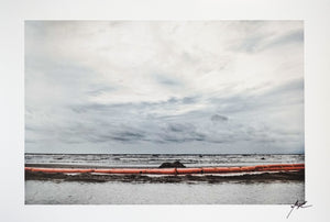 ocean with gray clouds and red barrier at shore line  Edit alt text