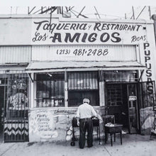 Load image into Gallery viewer, black and white photo of front of an old taqueria with man standing in front