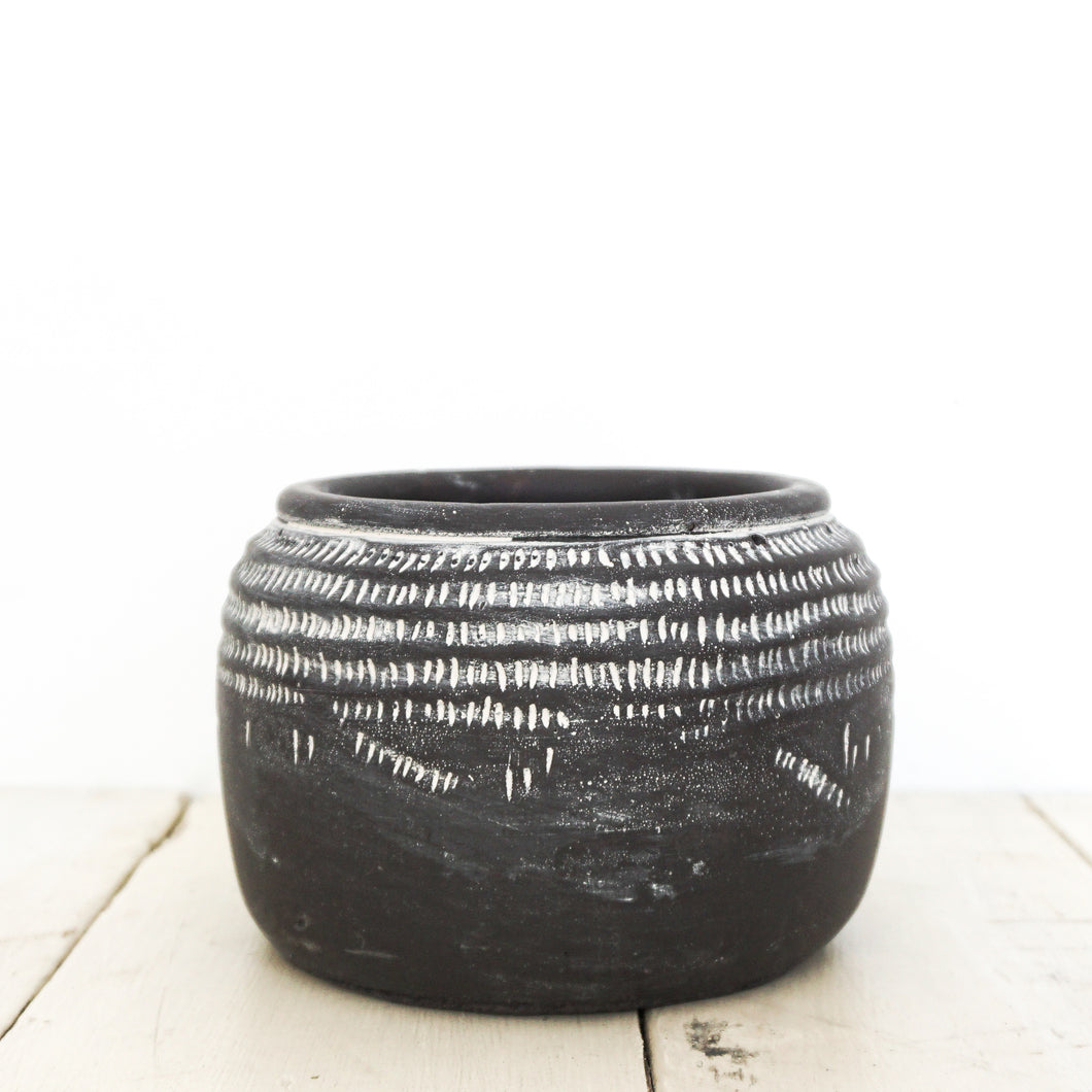 Black ceramic pot with white markings around top