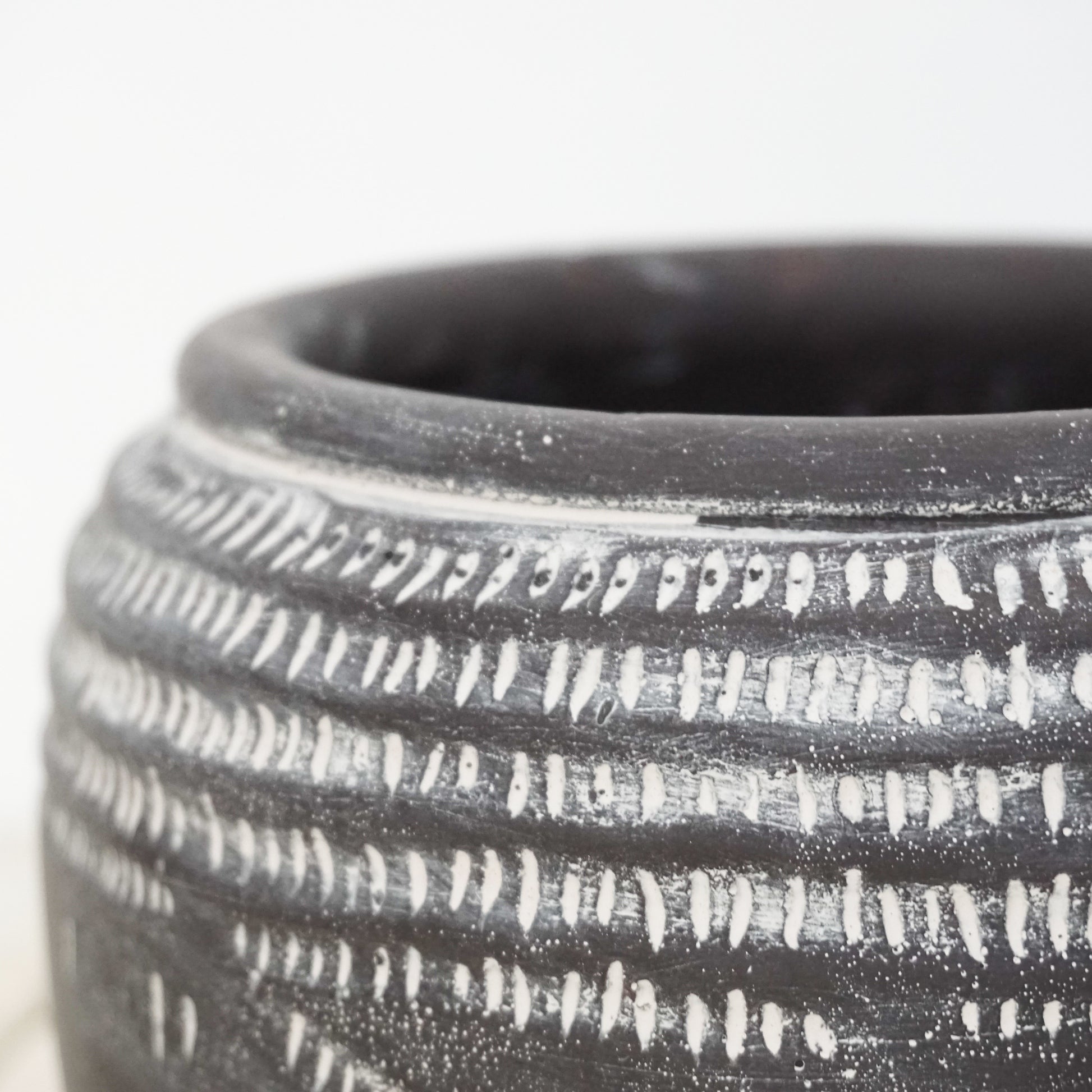 Black ceramic pot with white markings around top